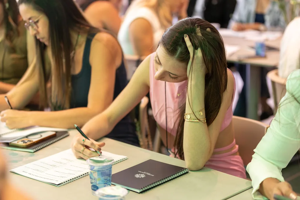 Participantes escrevem em seus cadernos durante a atividade.