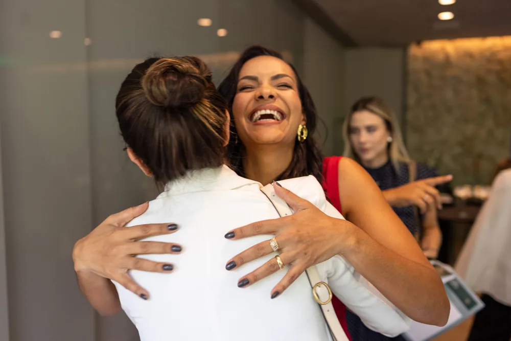 Daniela Rocha abraça uma participante, rindo.
